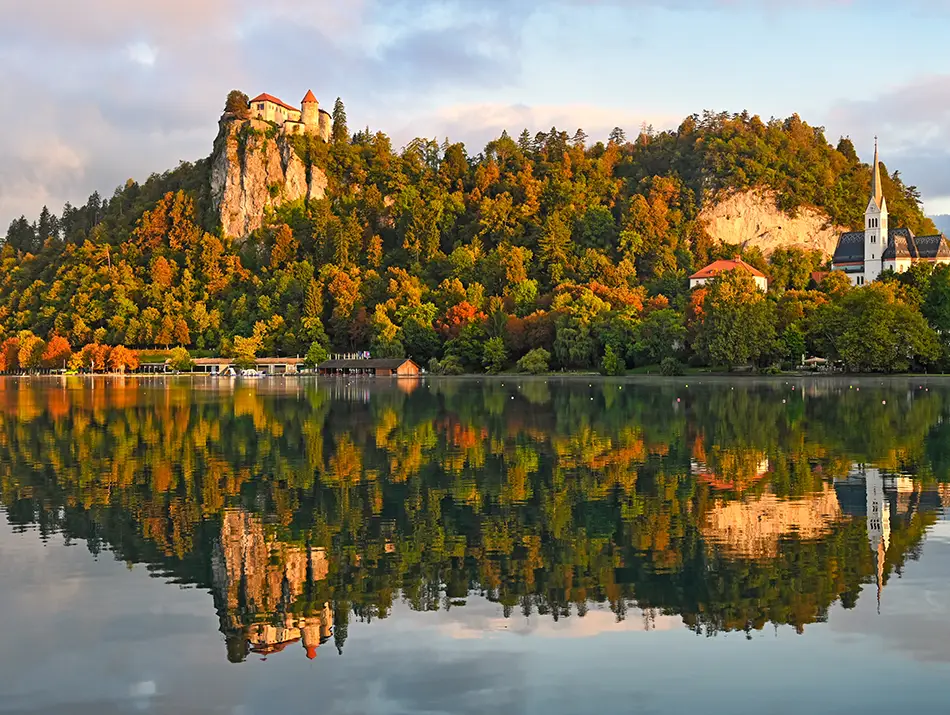 Fall Colors in Europe glow on mirror-still Lake Bled.