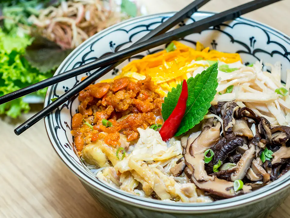 Clear broth with vermicelli topped with chicken, egg and Vietnamese sausage in Hanoi.