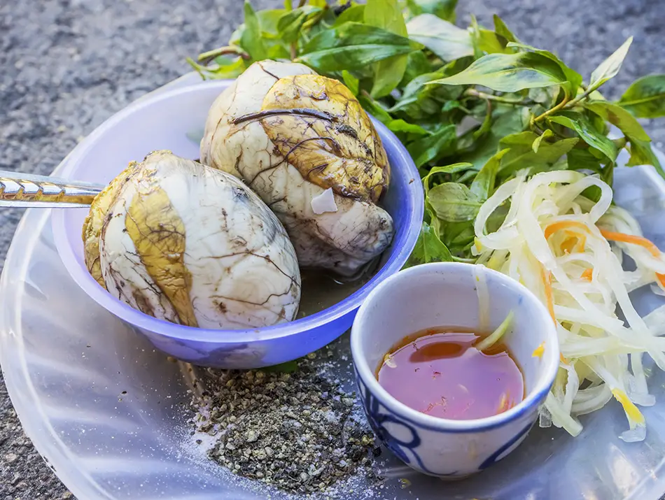Fertilized duck egg served with rau răm herbs and pepper salt.