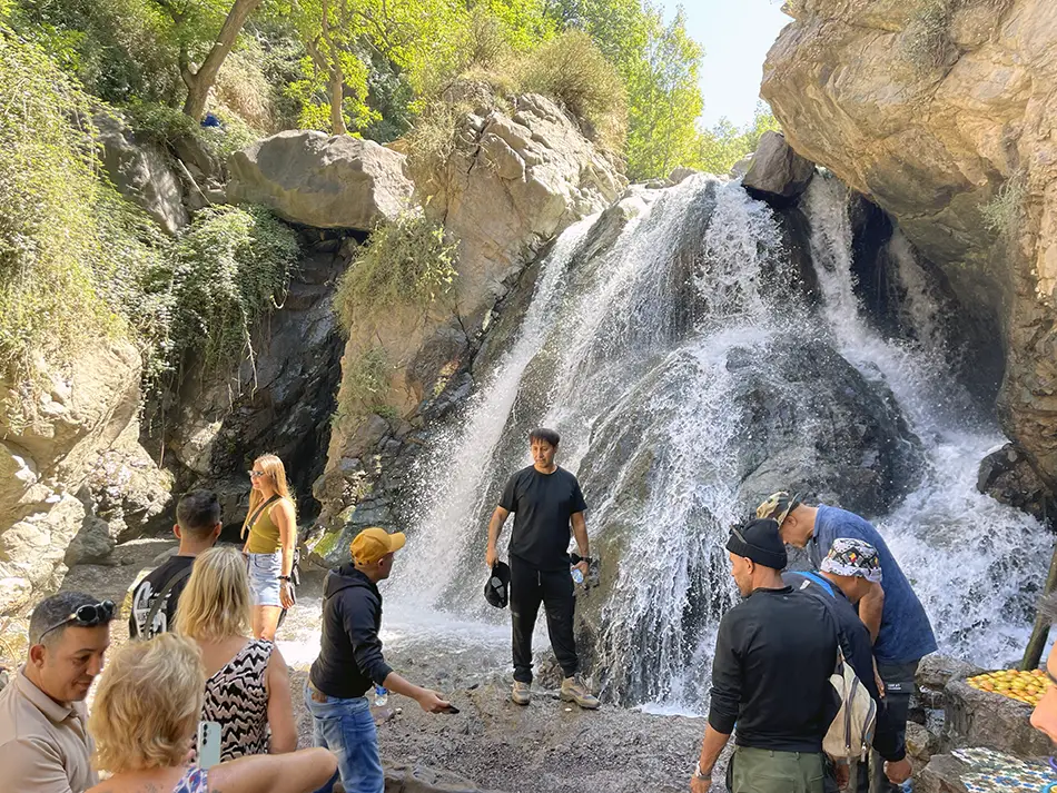 Tourists at the base of a waterfall, a best things to do in Imlil.