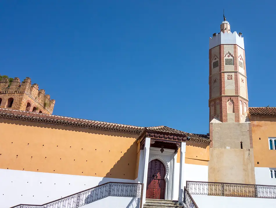 White minaret of the Grand Mosque standing tall against the clear sky.