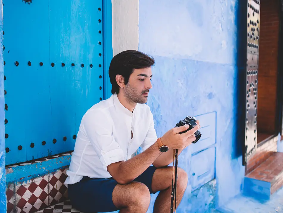 A traveler sitting next to a blue painted wall of medina