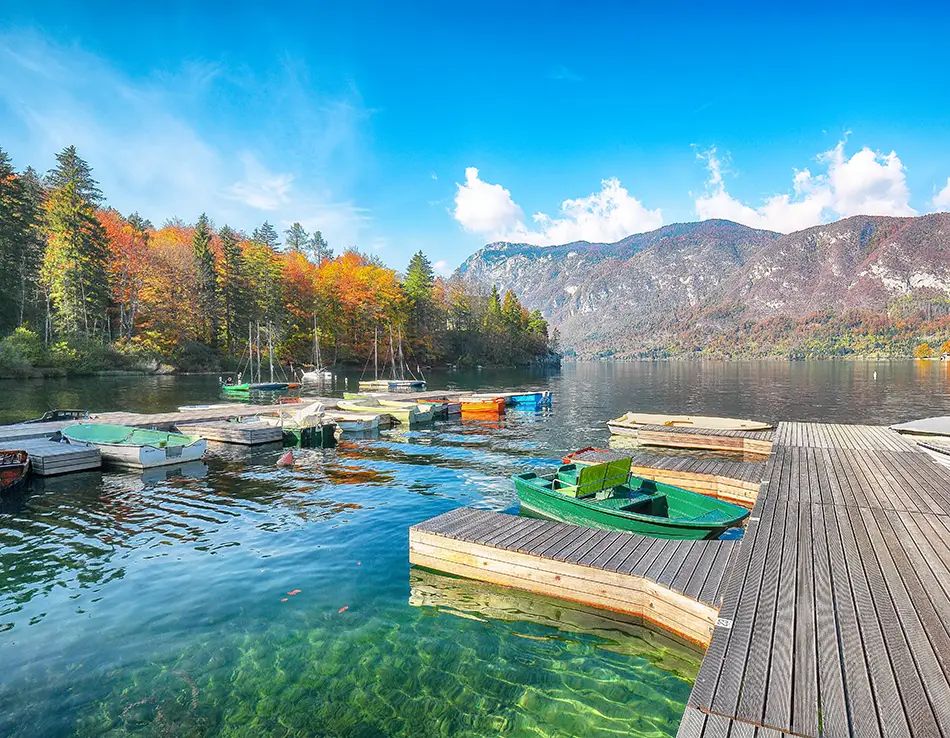 Emerald river in Triglav National Park framed by alpine peaks and autumn trees.