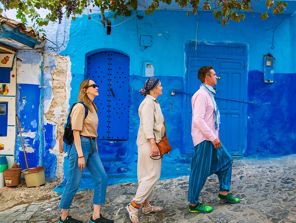 Tourists exploring a blue-painted alley, enjoying free things in Chefchaouen.