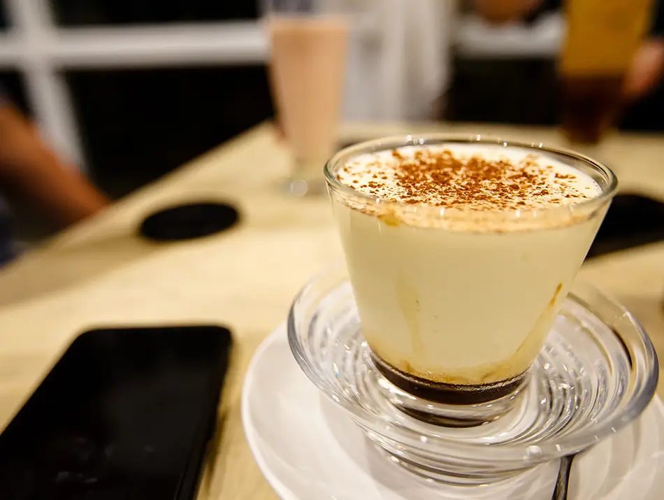 Creamy Vietnamese egg coffee topped with froth, served in a glass cup at a Hanoi café.