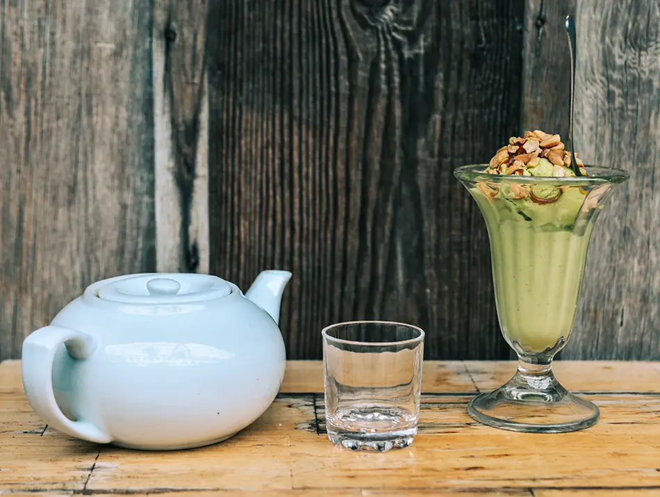 Creamy avocado ice cream sundae served with tea set on a wooden table