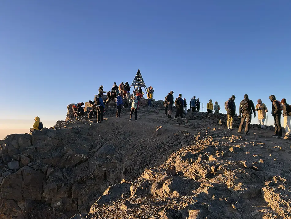 Travelers celebrating sunrise on a rocky summit, best things to do in Imlil.