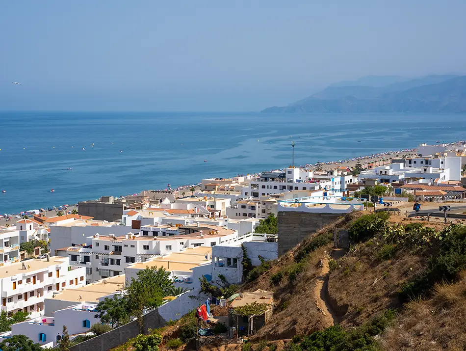 Seaside view of Oued Laou beach with waves and mountain backdrop.