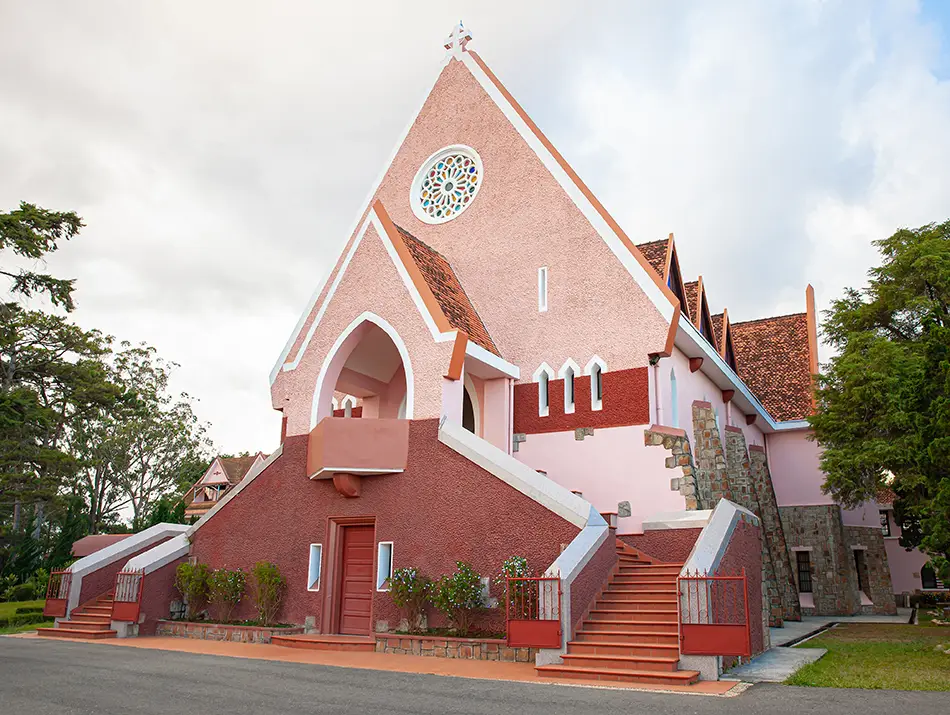Pink facade of Domaine de Marie Church under clear skies, one of the top religious places to see in Dalat.