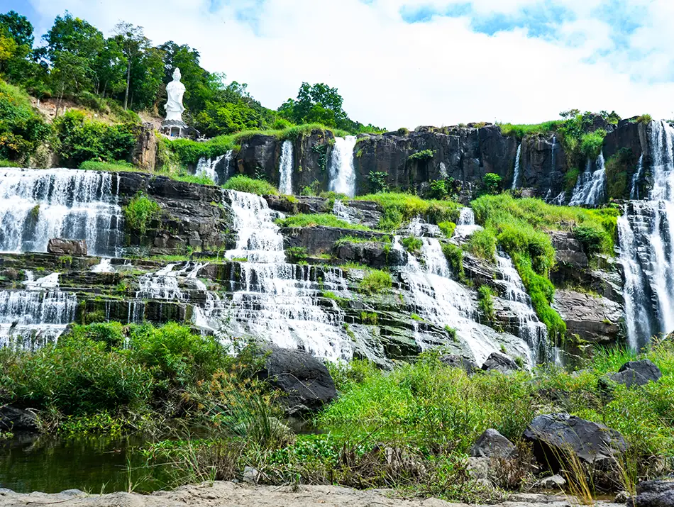 Multi-level cascade of Pongour Waterfall surrounded by tropical greenery