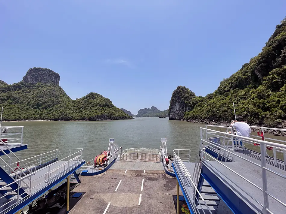 Public ferry sailing past karst cliffs, showing how to get to Cat Ba Island from Halong.
