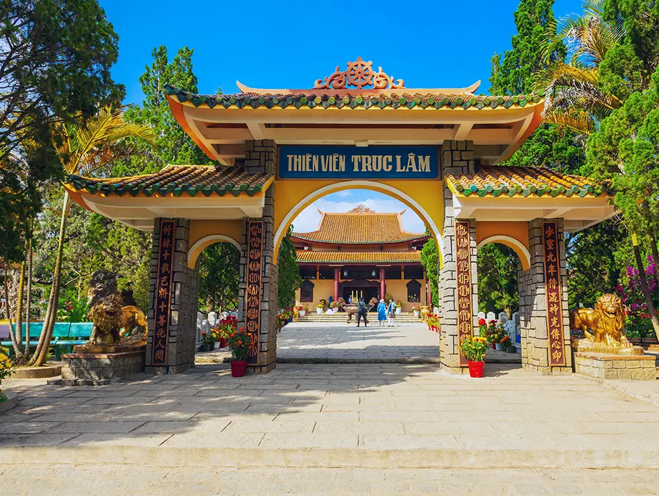 The ornate gate of Truc Lam Zen Monastery framed by pine forest