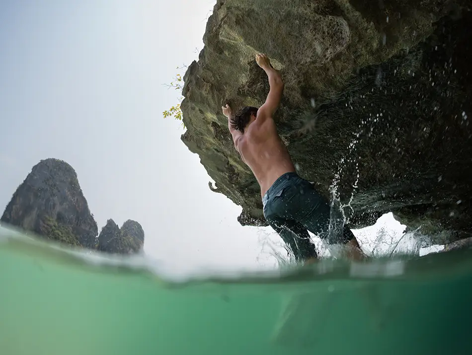 Climber scaling a rock face above the sea, an adventurous activity in Cat Ba Vietnam.