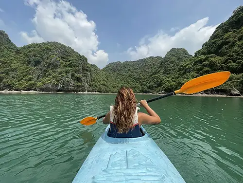 Traveler kayaking between limestone cliffs, a popular activity in Cat Ba Vietnam.