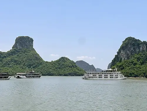 Boat passing limestone karsts during a Lan Ha Bay cruise, one of the best things to do in Cat Ba Vietnam.