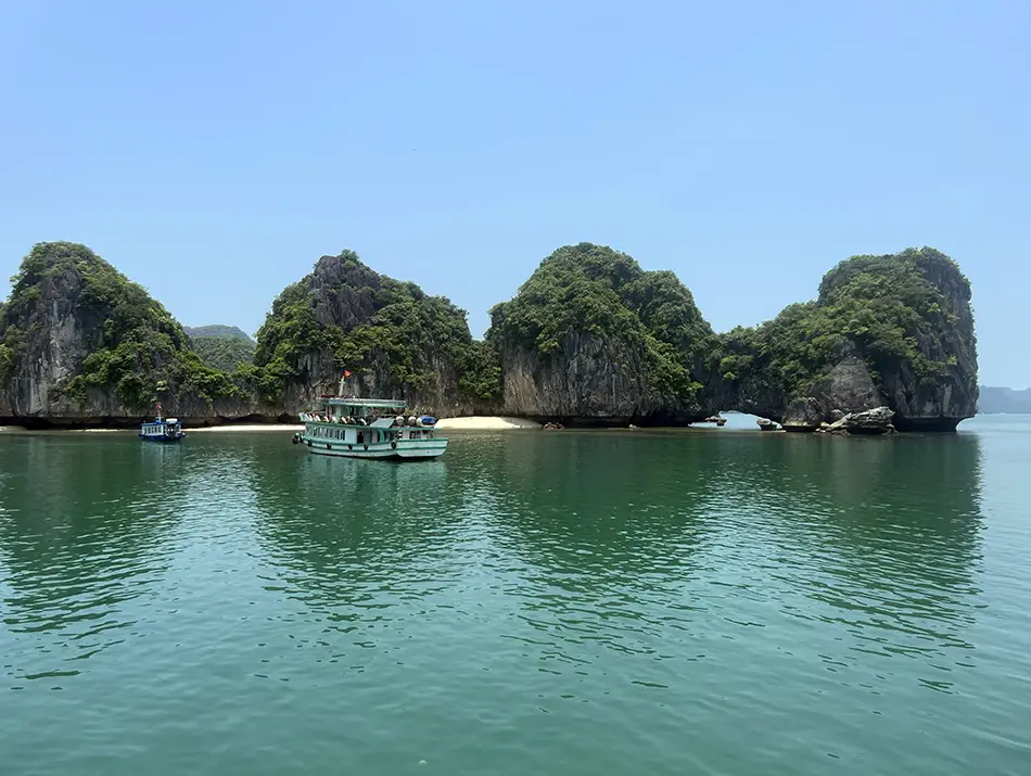 Emerald water reflecting limestone islets on a clear day in Lan Ha Bay.