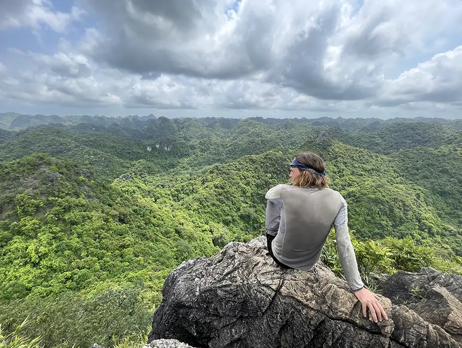 Hiker resting on rocks at Ngu Lam Peak, one of the top sights in Cat Ba Vietnam.