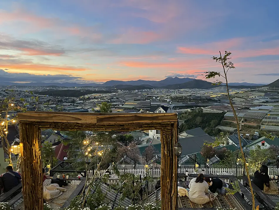 View of surrounding hills from a cozy cafe terrace at dusk, capturing soft sunset reflections.