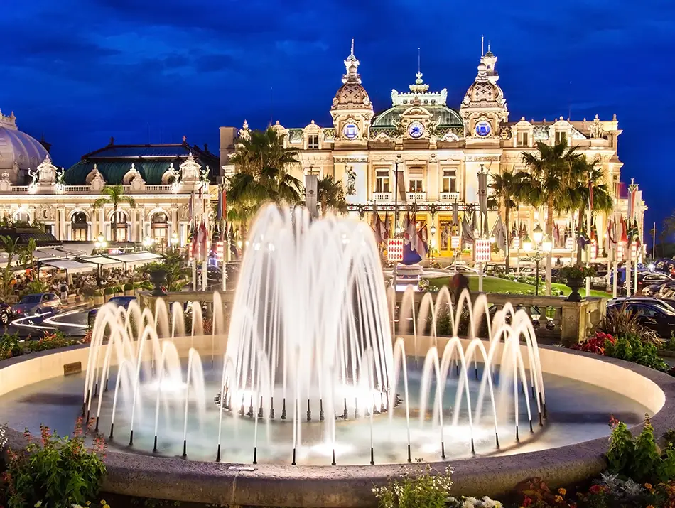 Illuminated casino facade and fountain under clear night sky.