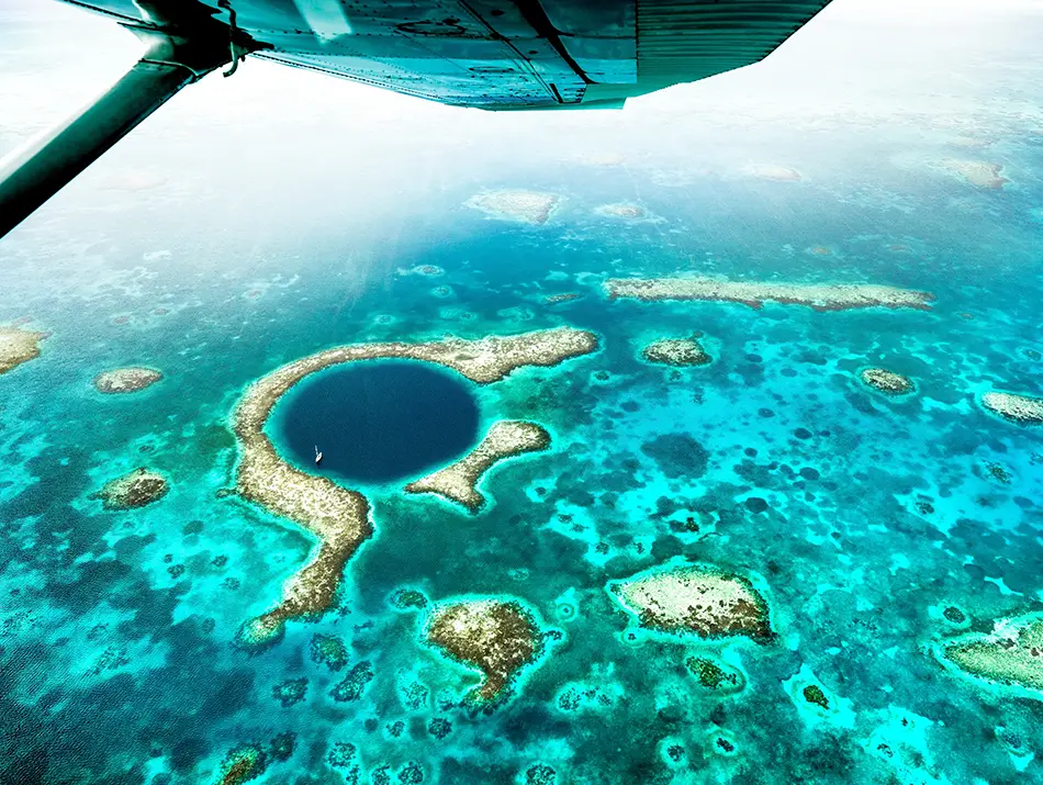 Aerial view of the Great Blue Hole, a dream travel destination over vibrant reef waters.