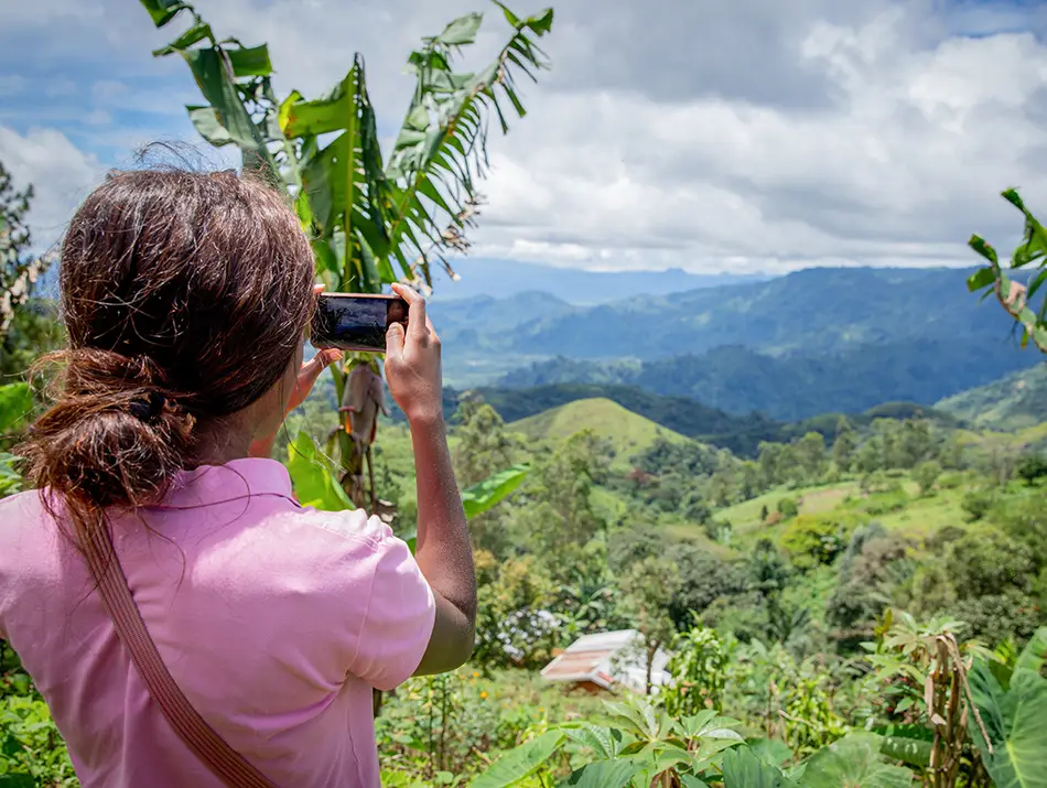 Traveler photographing lush highland valleys in a best adventure country setting.