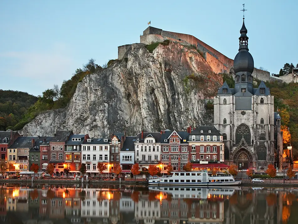 Riverside town below towering limestone cliff and citadel.