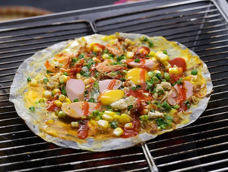Banh trang nuong, also known as Da Lat pizza, a popular and authentic Vietnamese street food to try.