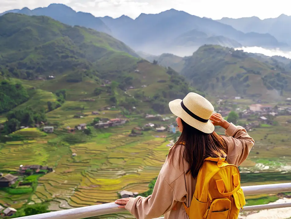 A traveler looks out over sweeping green rice terraces and misty mountain valleys, capturing one of the best things to do in Sapa.