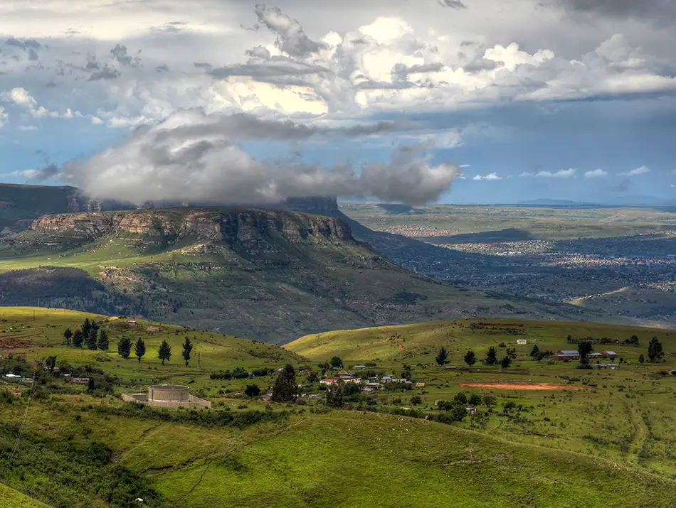 Rolling green highlands and distant peaks under soft clouds.