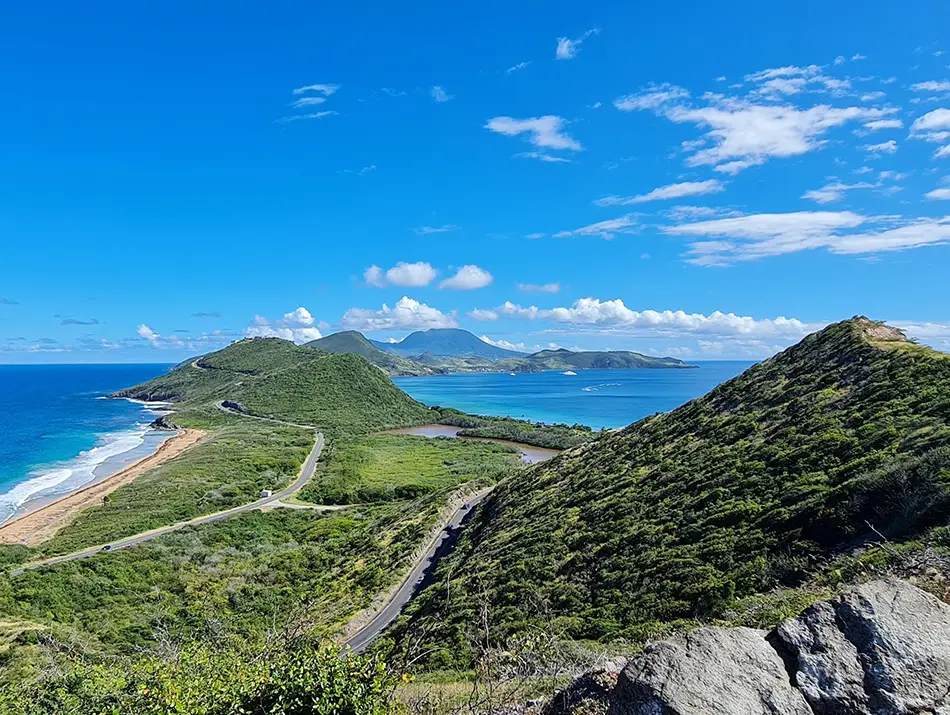 Panoramic coastal viewpoint surrounded by lush hills and turquoise water.