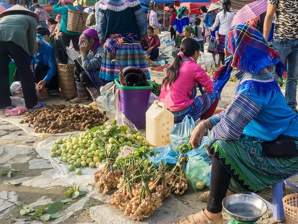 Vendors in colorful ethnic clothing gather at Bac Ha Sunday Market to sell fresh produce and goods.