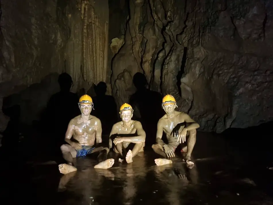 Travelers relax in the naturally buoyant mud chamber deep inside Dark Cave.