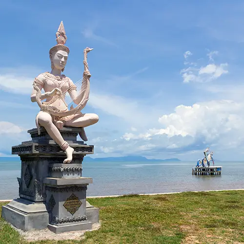 Seaside statue on a promenade overlooking calm waters in Kep.