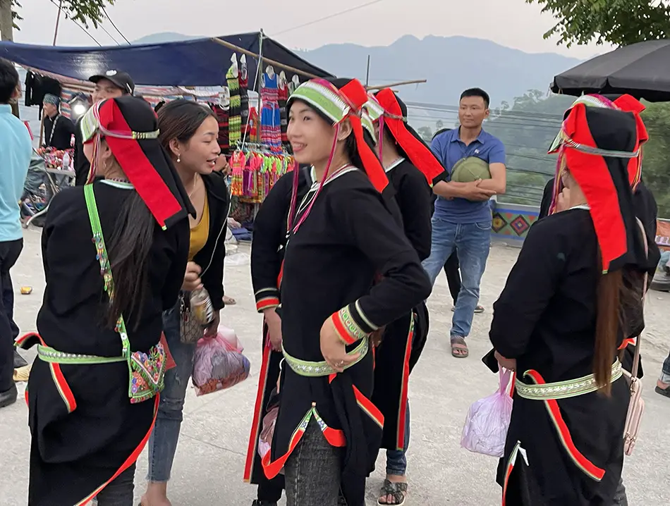 Women in traditional clothing chat at a busy highland market, reflecting the local culture in Sapa in Vietnam.