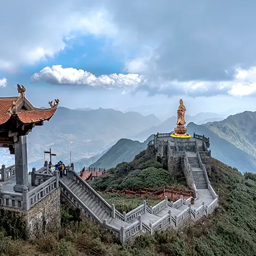 Stone stairways and a mountaintop temple overlook distant clouded peaks near the Fansipan summit.