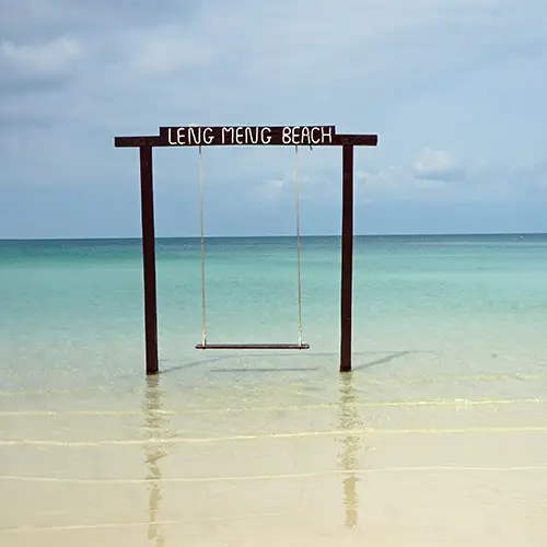 Wooden swing standing in shallow turquoise waters on Leng Meng Beach.