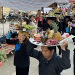 Villagers carrying trays of Vietnamese cuisine dishes as ceremonial festival offerings.