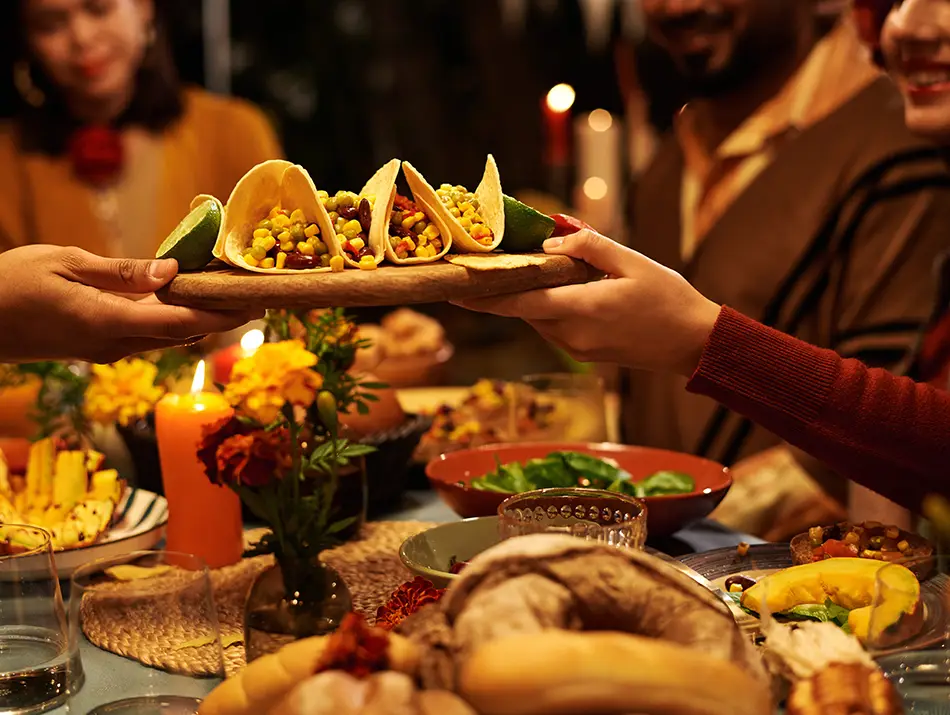 Hands passing a platter of tacos at a warm, communal meal in Mexico - the best foodie country for 2026.