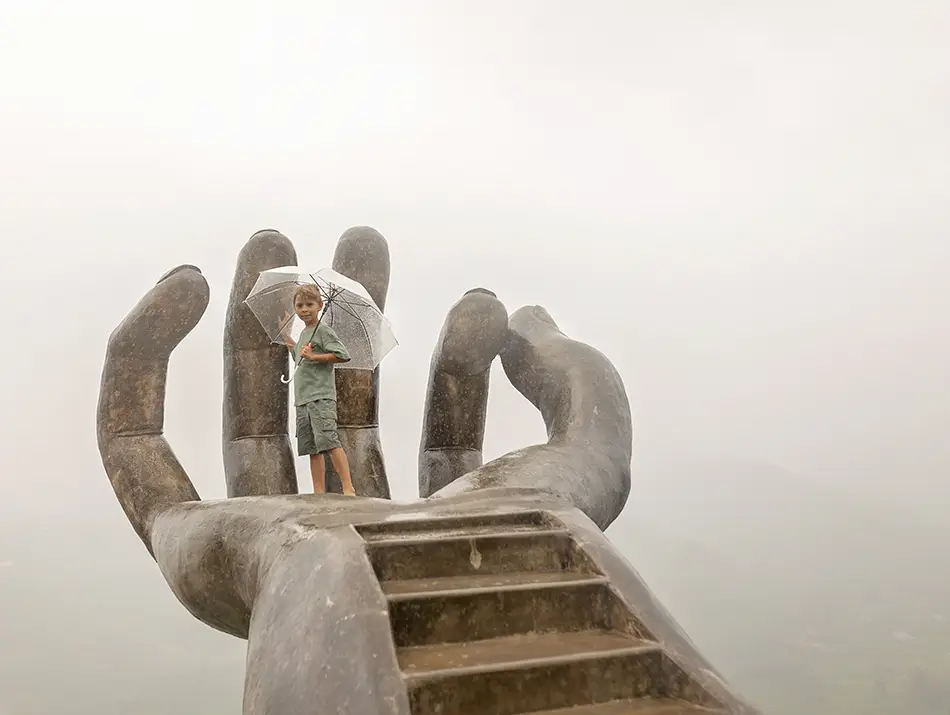A visitor stands on the giant hand-shaped platform overlooking Sapa’s misty valley landscape.