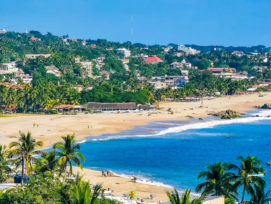 Golden beach and palm-dotted hills in Puerto Escondido, Mexico, perfect for ocean lovers.