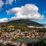 A wide panoramic view of Sapa town surrounded by bright clouds and terraced hills.