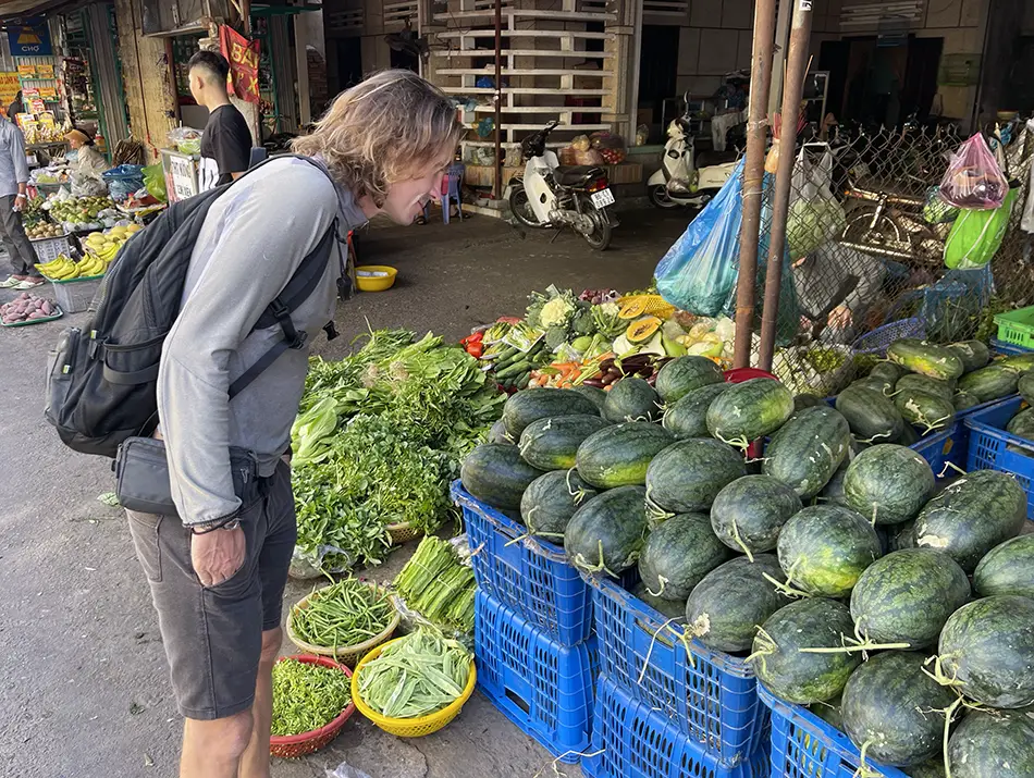 Traveler examining fresh watermelons at a local market in Vietnam