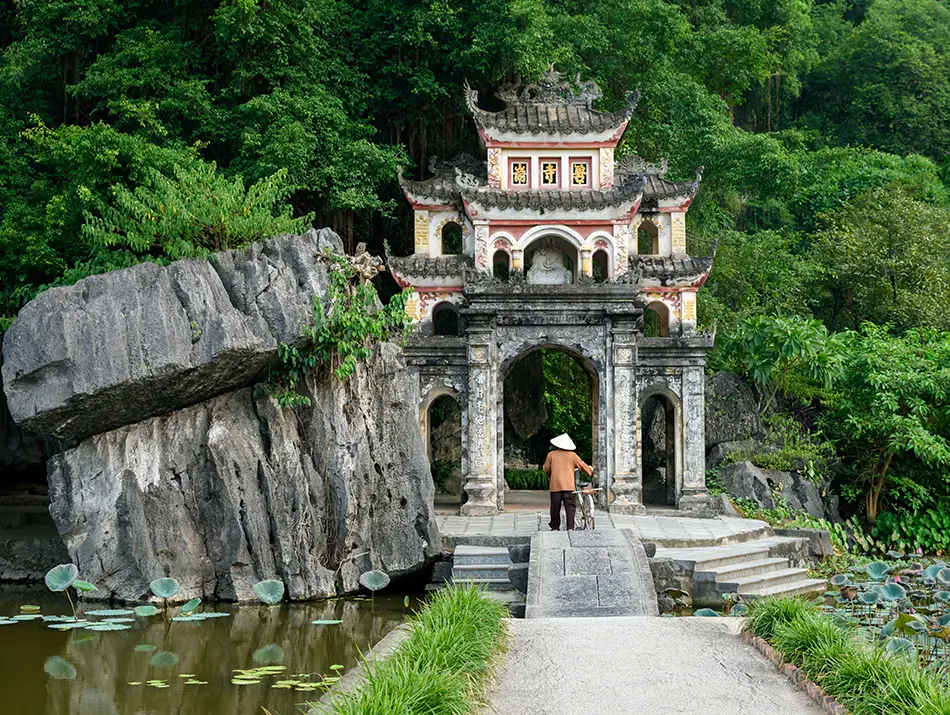 Historic stone gate at Bich Dong Pagoda set against limestone cliffs, a cultural attraction in Ninh Binh.