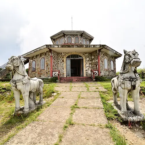 An old French-era villa with stone horse statues lining the path to its entrance.