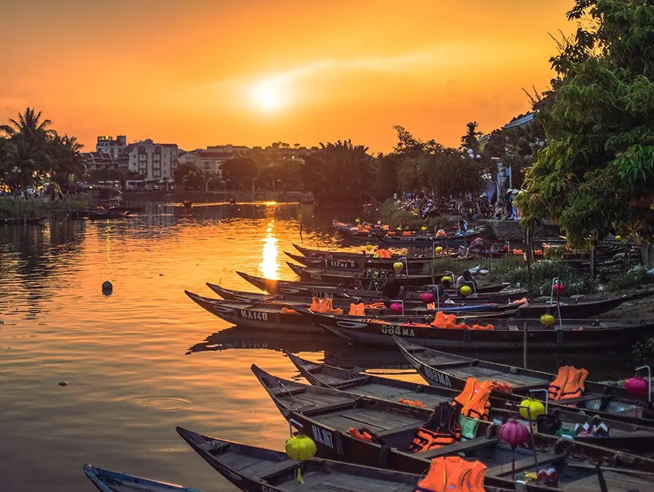 Riverside boats at sunset near eateries, highlighting best sunset spot in Hoi An