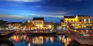 Colorful lantern-lined street with yellow houses and boats showcasing best things to do in Hoi An.