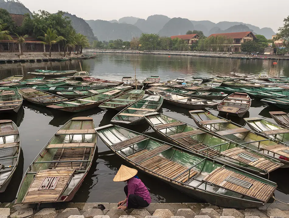 Dozens of small boats packed together at a riverside pier with karst hills behind.