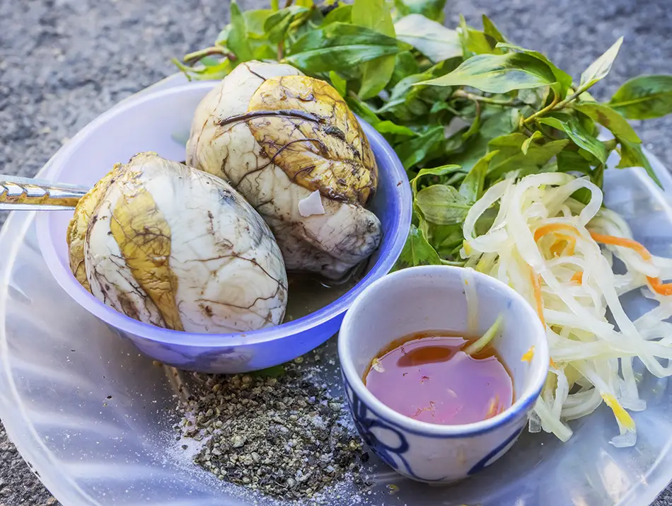 Fertilized duck eggs served with herbs, lime, and seasoned dipping sauce.