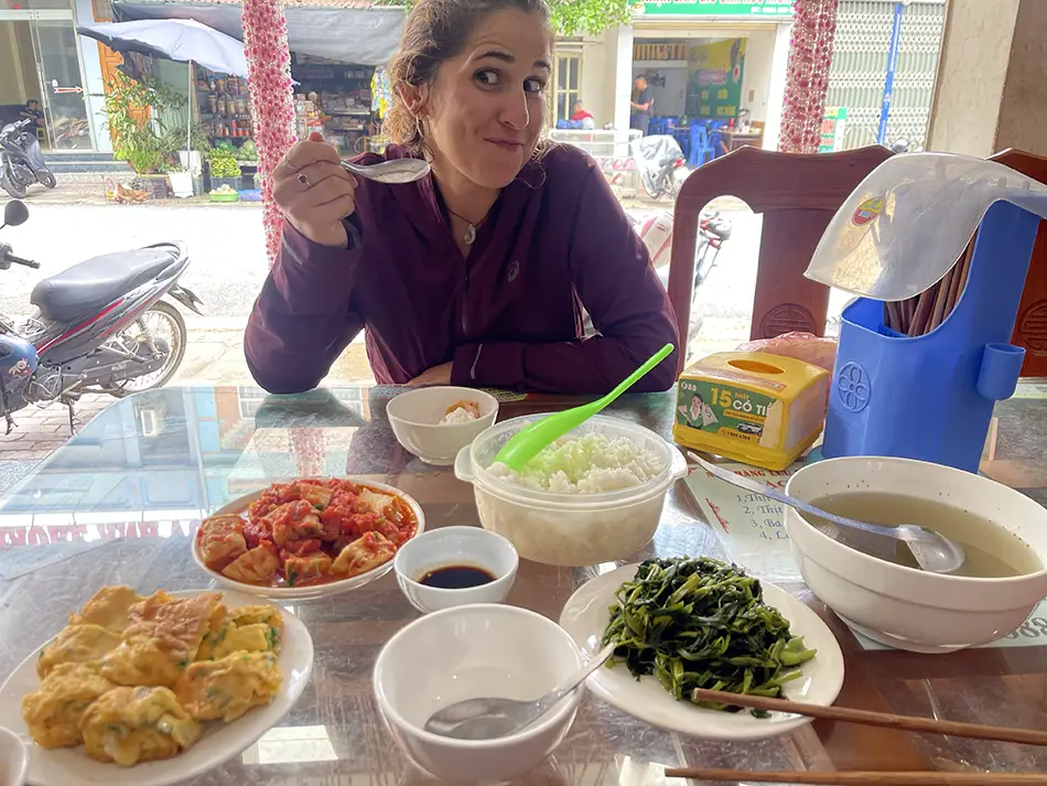 Traveler sampling local dishes to try in Ninh Binh at a small roadside restaurant table.