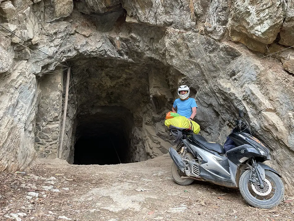 Motorbike parked at rocky cave entrance.